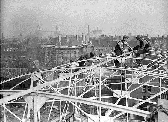 Abbey Street, workmen perch on top of scaffolding to repair the roof of the Docklands Club, Bermondsey, Tower bridge in the distance.  1  X.jpg