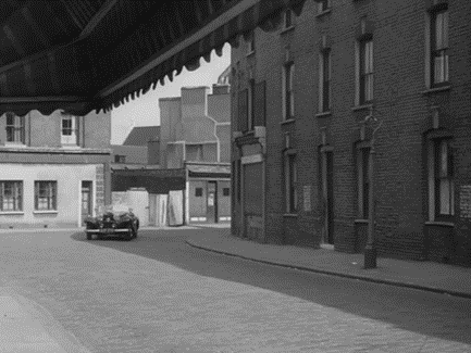 Film The Ringer 1952. St. Marychurch Street, Rotherhithe, looking at No 12a to the left of the background terrace.  Pic 3.  X..png