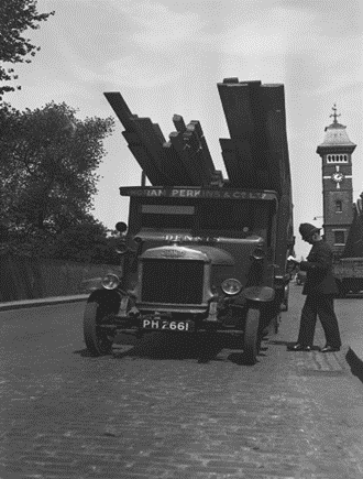 Surrey Docks, a dock constable checking an Ingram Perkins & Co Ltd, Timber lorry at the gates of the Surrey Docks, 1934.  X..png