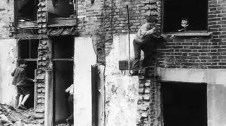 2 Children play in the ruins of a house on a bomb site in Bermondsey, 1954.  X..png