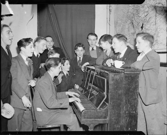 Bermondsey 1944 Boys at the Canterbury Club of the Oxford and Bermondsey Boys Club take part in a sing-song round the piano. The Canterbury Club is on Webb Street, Bermondsey.jpg