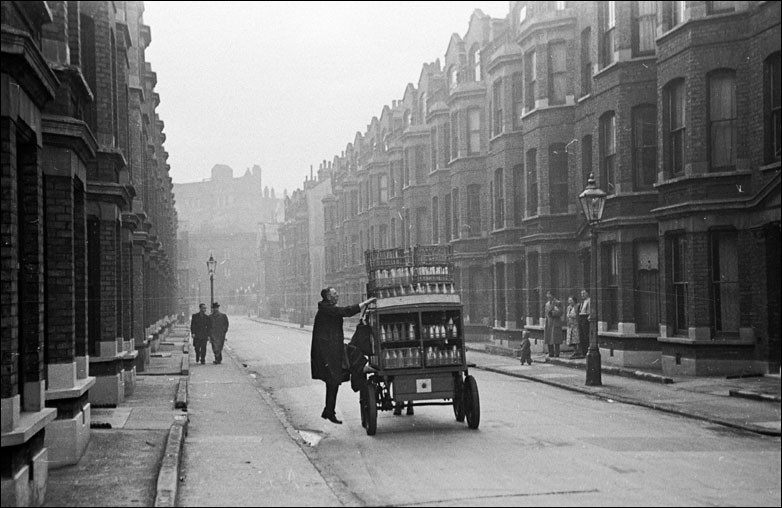 A man climbs onto a Southwark milk cart near the Elephant and Castle in South London..jpg