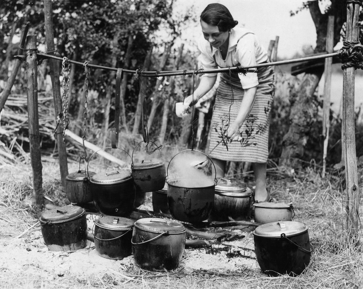 A woman prepares a meal for hop pickers at the Whitbread hop camp in Paddock Wood, Kent. (1937).jpg