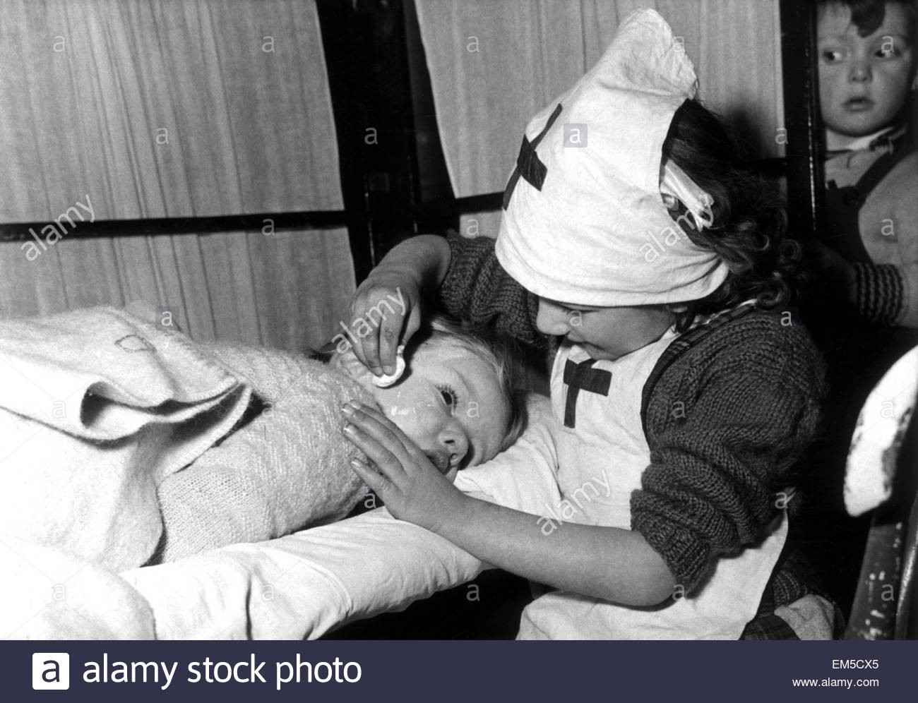 Grange Road, Kintore Way Nursery School in Bermondsey 1955. Three year old Brenda Aukett being checked over by nurse Janice Garry, aged 5. X.jpg