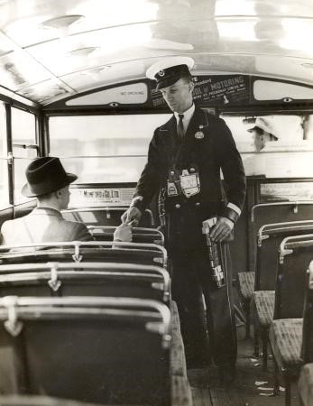 Conductor (badge no N65108) issuing a ticket to a passenger on the lower deck of a bus at London Bridge; the conductor has a Bell Punch ticket machine .  X.jpg