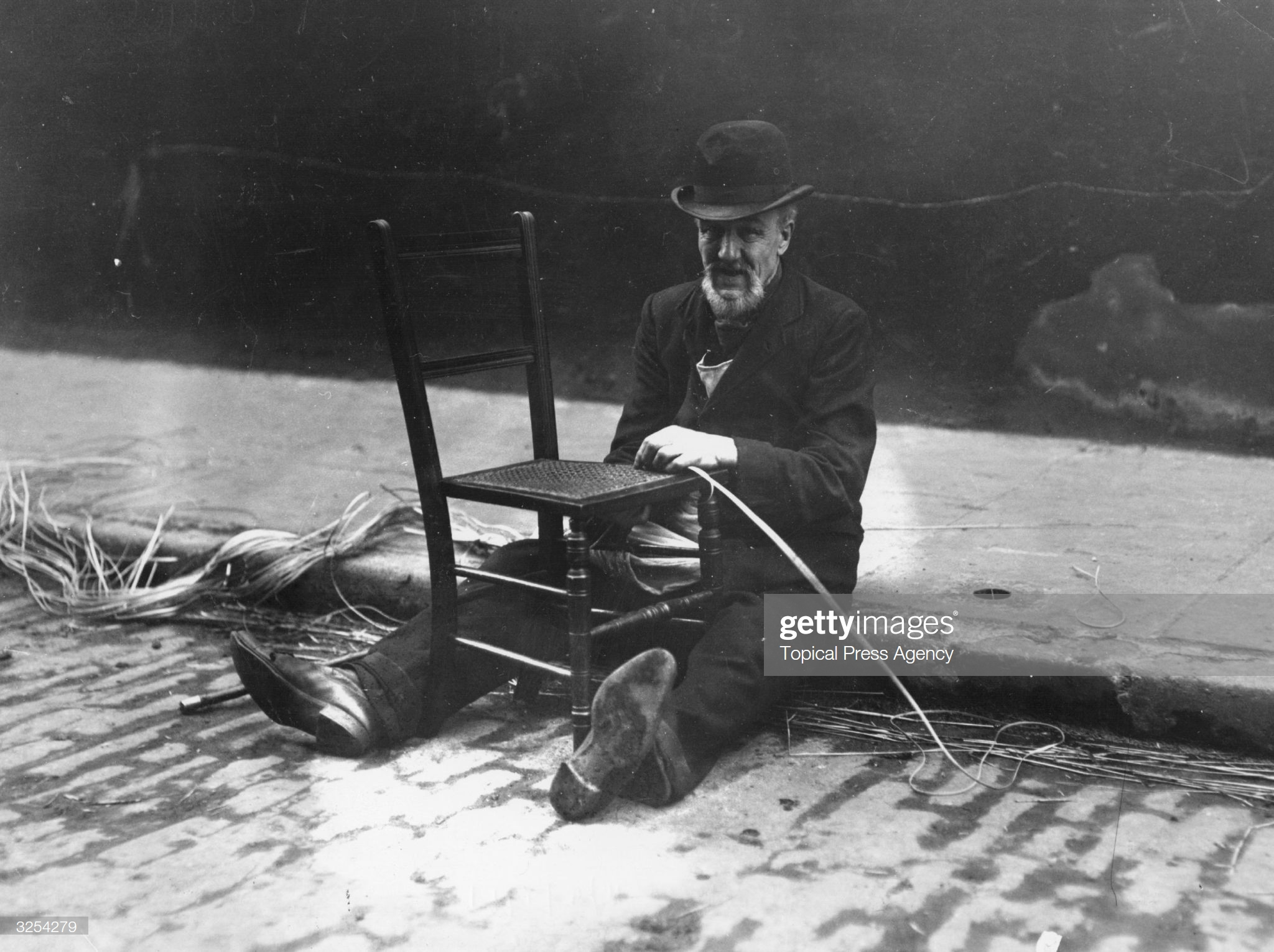 Tabard Street. A chairmender at work re-weaving the seat of a chair in Tabard Street c1911.  X.png