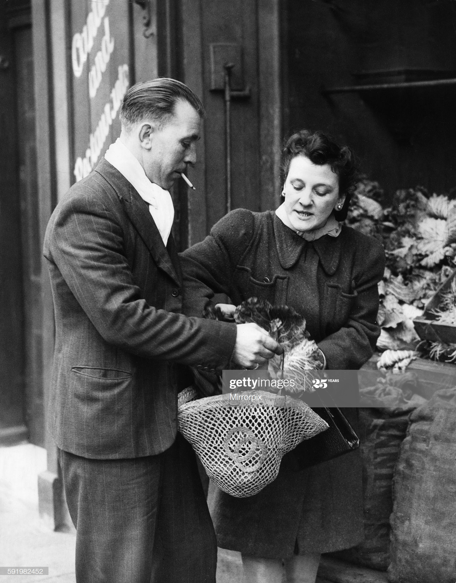 Private Ted Saunders of the 2nd Army out shopping with his wife Margaret in Bermondsey while on leave during the Second World War. 7th January 1945.  X.png